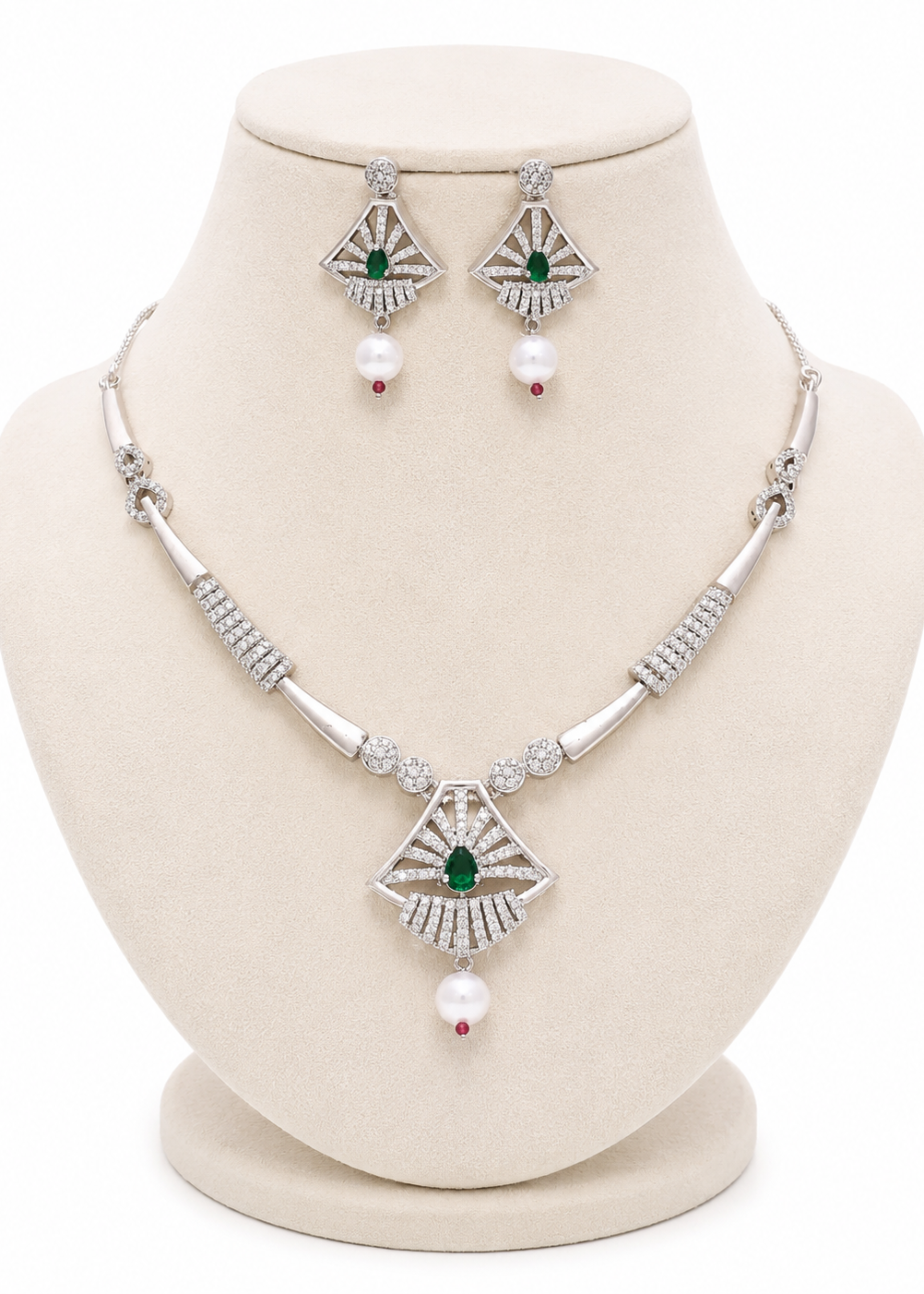 Silver-tone jewelry set on a cream display bust, featuring a necklace and matching earrings with green stone accents and white pearl drops.